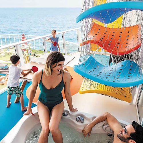 Family relaxing in a private balcony hot tub aboard a Royal Caribbean suite, enjoying luxury living with ocean views.