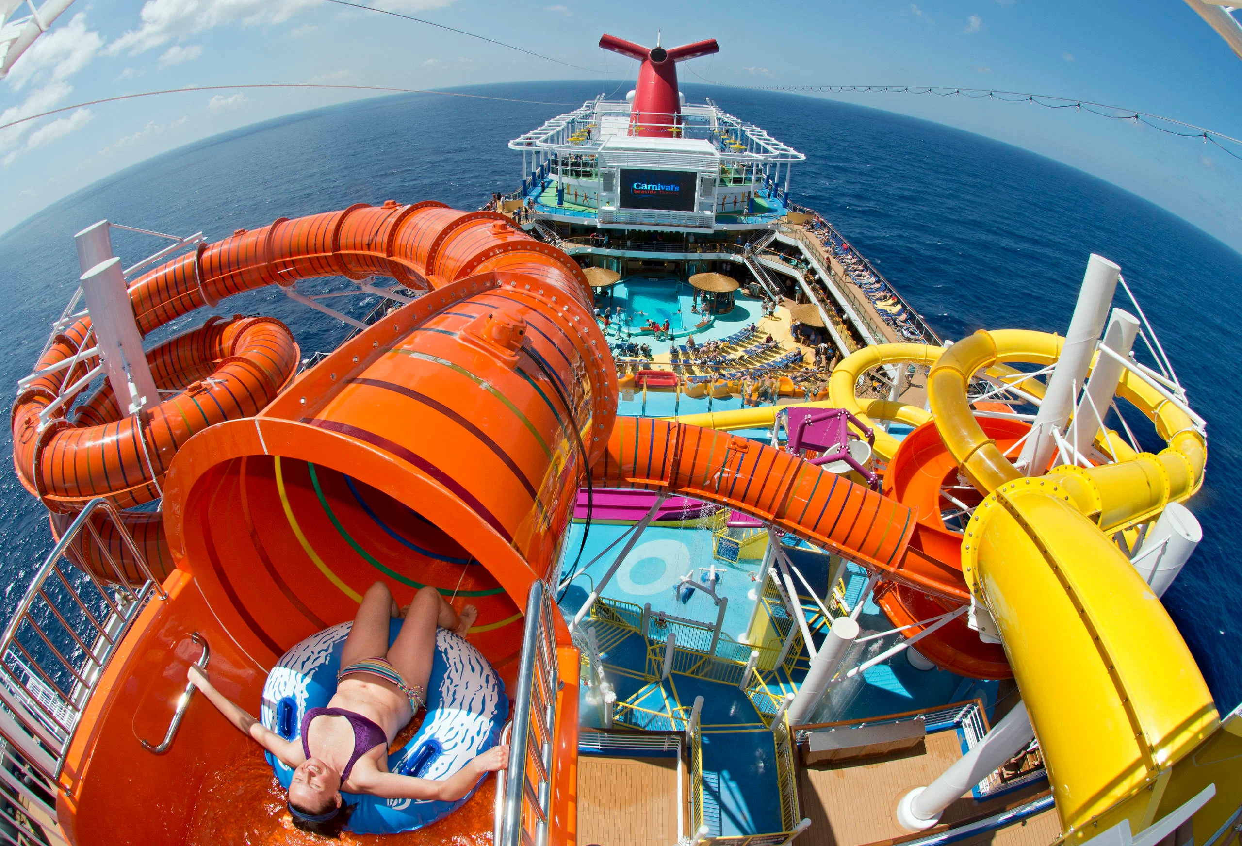 Guests splashing down waterslides and relaxing by the pool on a Carnival Cruise, enjoying sun-soaked fun at sea.