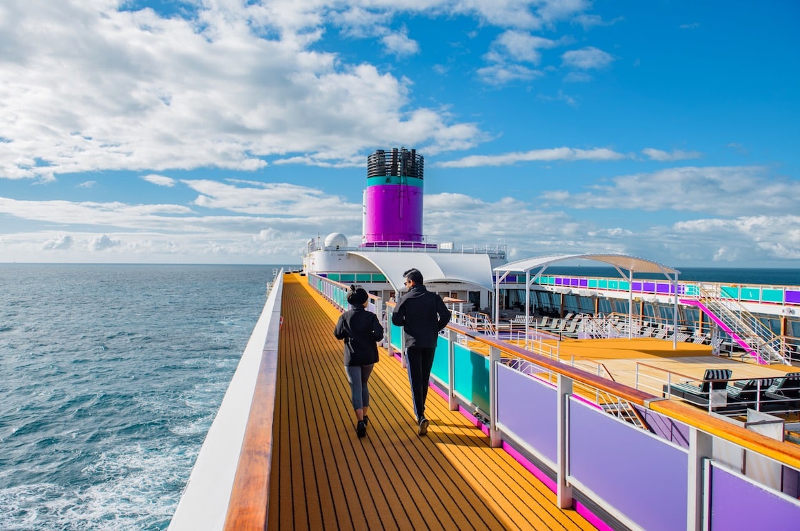 Adults jogging on the open-air running track aboard Ambassador Cruise Line, staying active with ocean views and fresh sea air.