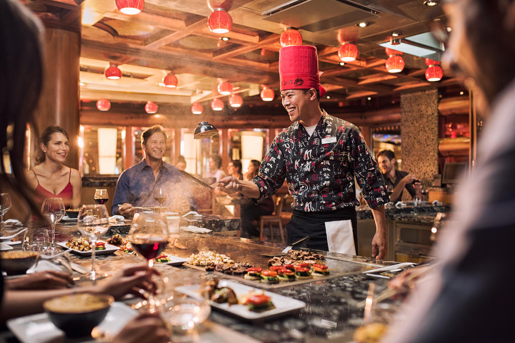  Guests enjoying a live Japanese teppanyaki show onboard, with chefs grilling fresh ingredients and performing tableside flair.