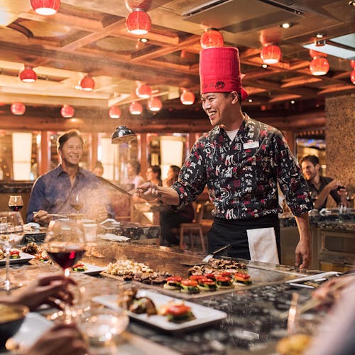 Guests enjoying a live Japanese teppanyaki show onboard, with chefs grilling fresh ingredients and performing tableside flair.