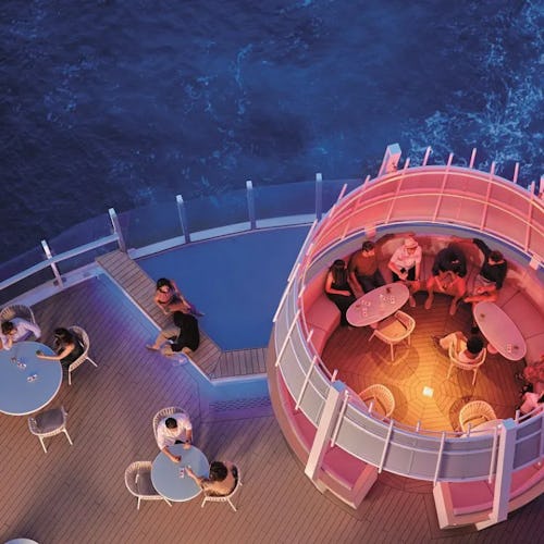 Bird’s-eye view of a stylish sun deck aboard Costa Cruises, featuring pools, loungers, and vibrant Italian design overlooking the sea.