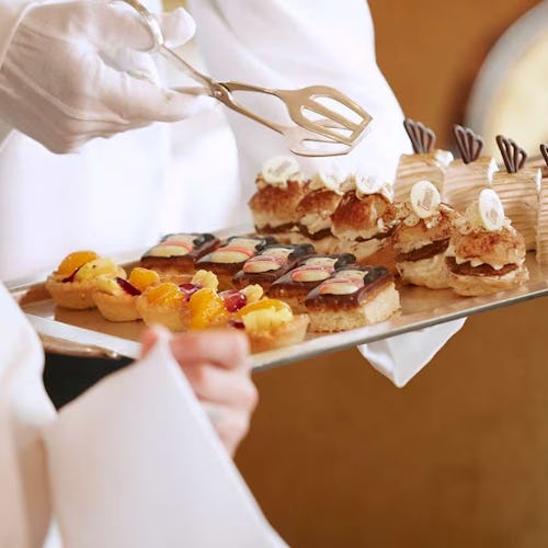 Guests enjoying traditional afternoon tea aboard Cunard, with fine china, finger sandwiches, and white-gloved service in an elegant setting.