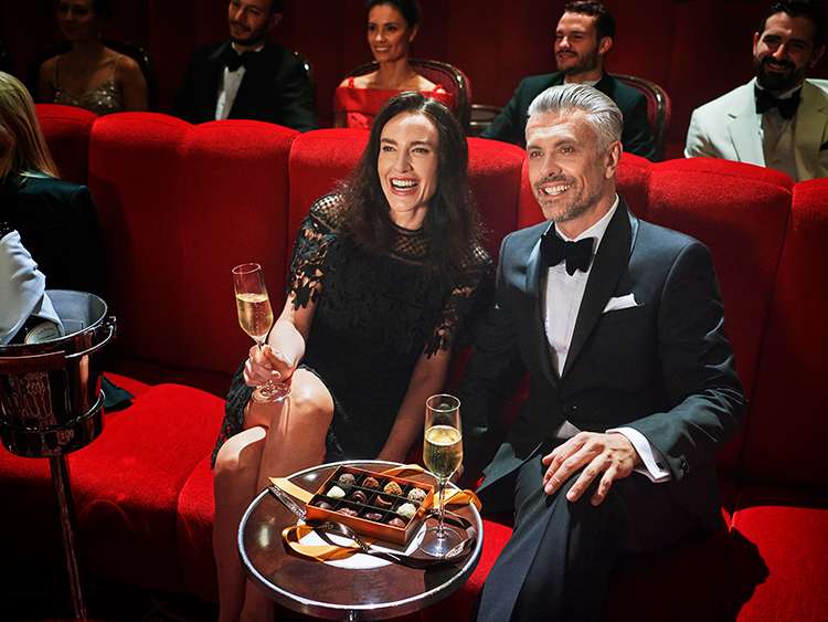  Couple enjoying a live performance in the Royal Court Theatre aboard Cunard, experiencing world-class entertainment at sea.
